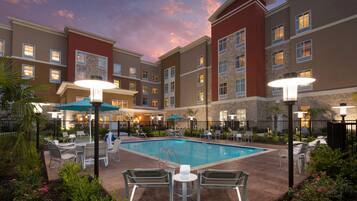Hotel com piscina, área de estar ao ar livre e céu ao pôr do sol.