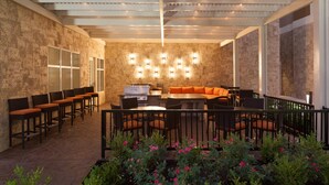 Une terrasse extérieure avec des murs en pierre, un barbecue et des sièges.