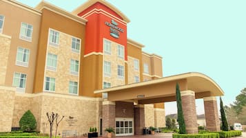 Un hotel con fachada roja y beige, una entrada cubierta y un letrero que indica una altura libre de 14 pulgadas y 6 pulgadas.