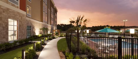 A hotel with a pool, a pathway, and a well-maintained garden.