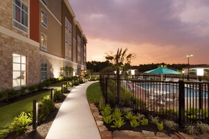 Un hotel con piscina, un sendero y un jardín bien cuidado.