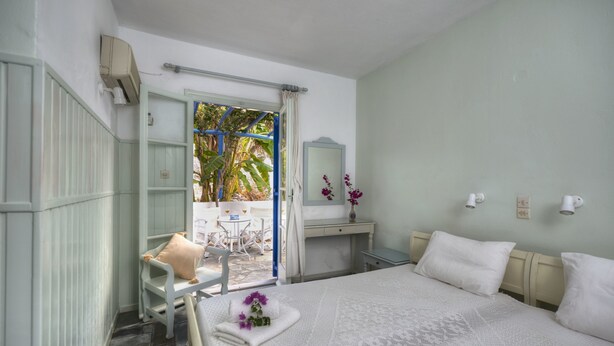 Una habitación de hotel con cama, escritorio, silla y ventana con cortinas.