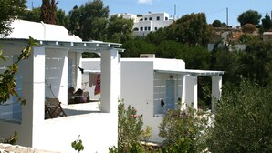 Un edificio blanco con un espacio de estar techado al aire libre y un pequeño jardín.