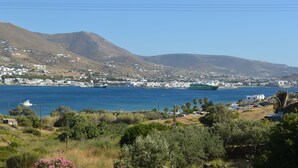 Un pueblo costero con edificios blancos, una masa de agua y montañas al fondo.