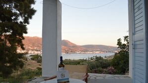 Un patio con una mesa y sillas, una botella de vino y un menú. Se aprecia una masa de agua y montañas a lo lejos.