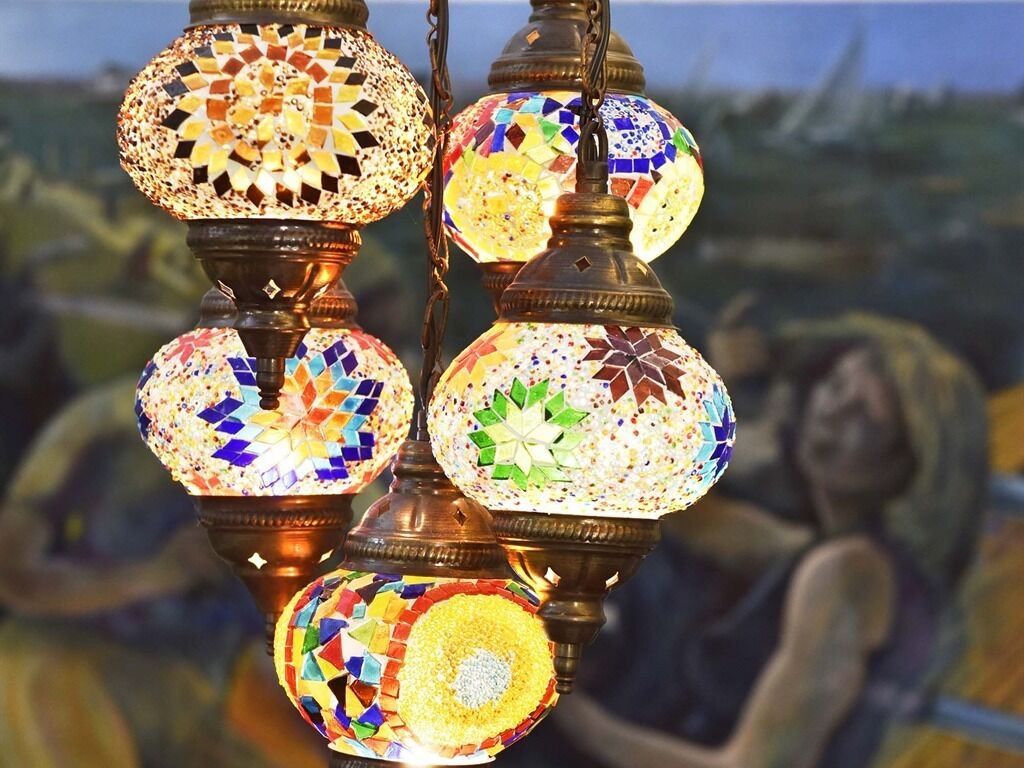 A series of colorful mosaic lamps with a traditional design, hanging from a structure.
