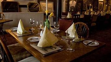 A dining table set with white napkins, wine glasses, and a vase with yellow flowers.