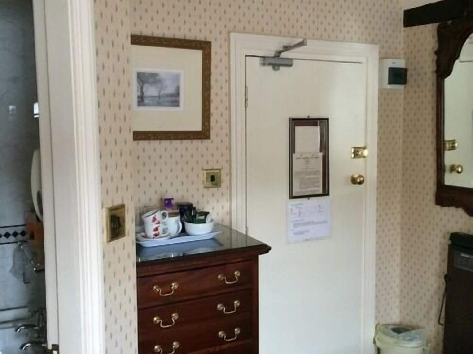 Una habitación con un aparador de madera, una puerta con un aviso y un cuadro en la pared.