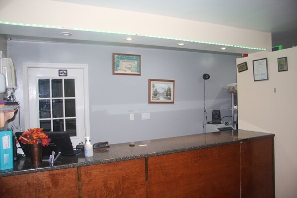 A reception area with a wooden counter, a white door, and framed pictures on the wall.