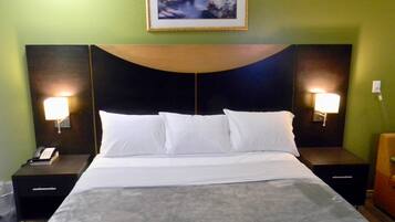 Habitación de hotel con una cama grande, dos mesitas de noche con lámparas, un teléfono y un cuadro enmarcado en la pared.