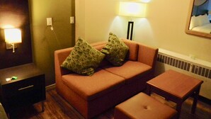 Una habitación acogedora con sofá, dos almohadas, una mesita y una lámpara.