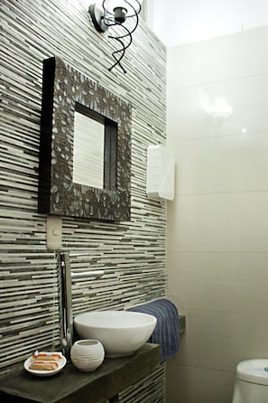 Une salle de bain dotée d’un lavabo moderne, d’un miroir décoratif et d’un porte-serviettes.