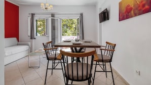 A dining area with a table set for four, surrounded by wooden chairs, a glass coffee table, and a white sofa. - Oasis Exclusive  (Parga)