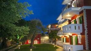A hotel with a curved balcony, a stone pathway, and a well-maintained lawn. - Oasis Exclusive  (Parga)