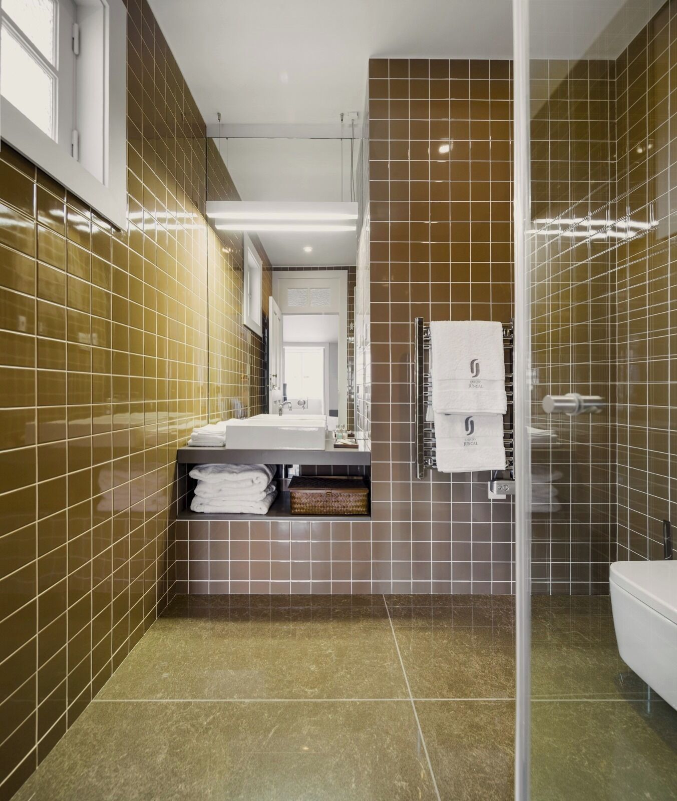 A modern bathroom with a glass partition, a sink with a mirror, and a towel rack.