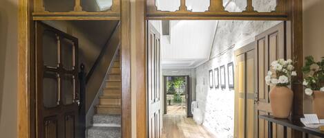 Una escalera de madera que conduce a un pasillo con pared blanca y suelo de madera.
