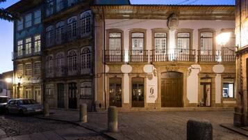 Un edificio histórico de varias plantas, con una entrada central y una puerta grande, y un balcón en el segundo piso.