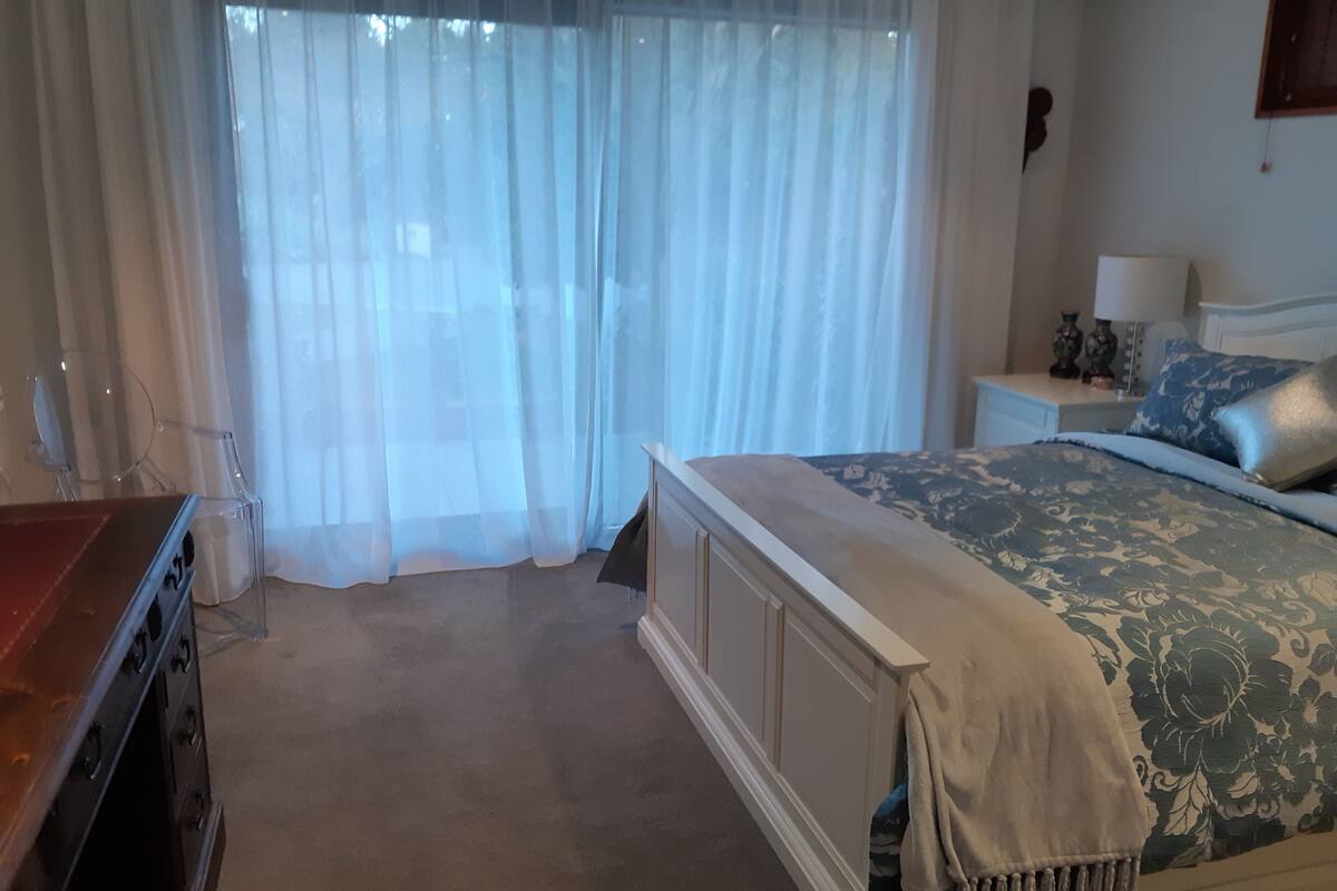 Makuuhuone, jossa on sänky, yöpöytä, lamppu ja lipasto.