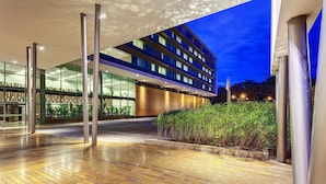 A modern hotel entrance with a glass facade, a wooden deck, and a well-lit outdoor area. - Estelar Villavicencio Hotel & Centro de Convenciones (Villavicencio)