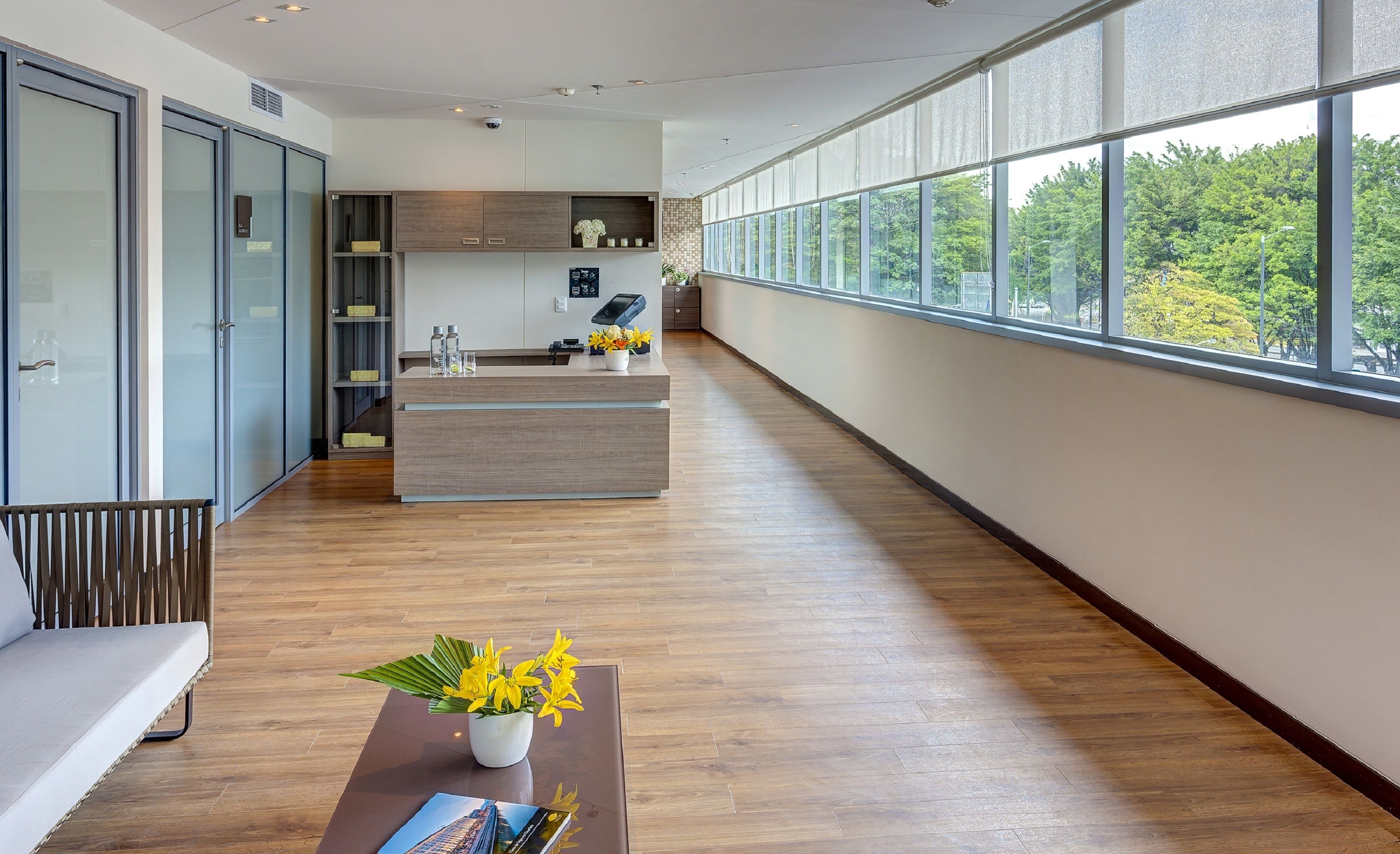 Une cuisine moderne dotée d’un îlot central, de planchers en bois et de grandes fenêtres offrant une vue sur la verdure.