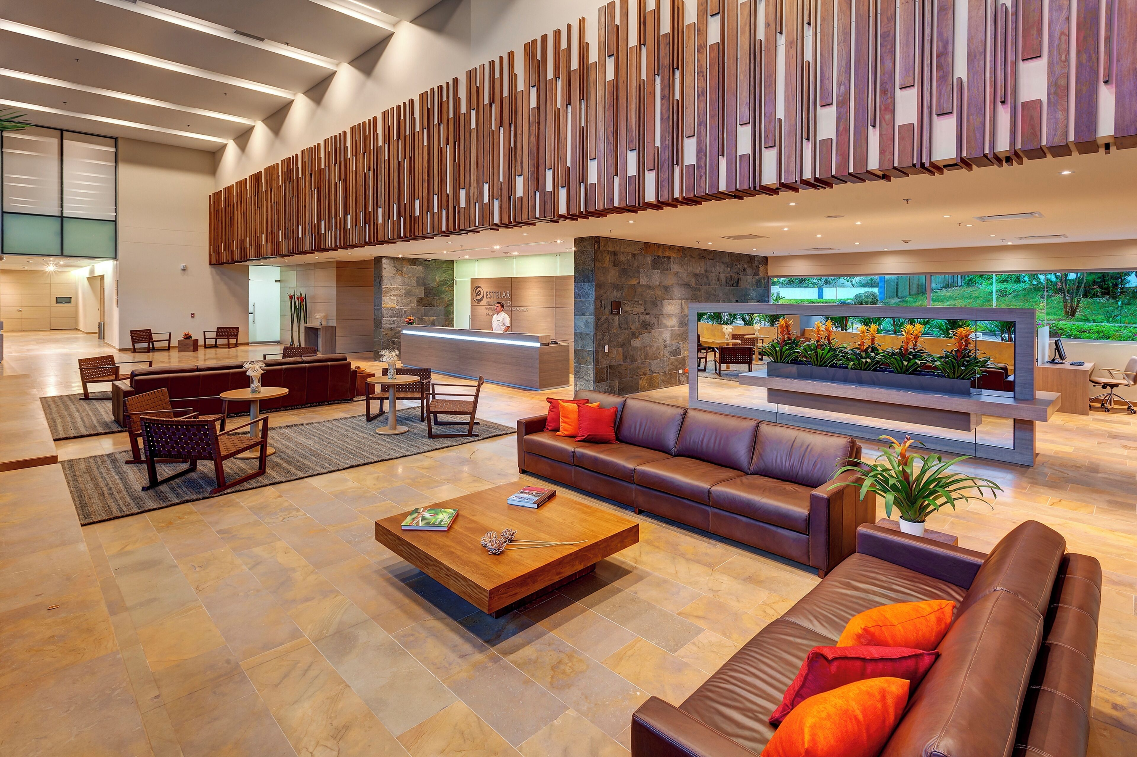 A spacious lobby with a reception desk, seating area, and a large TV screen.