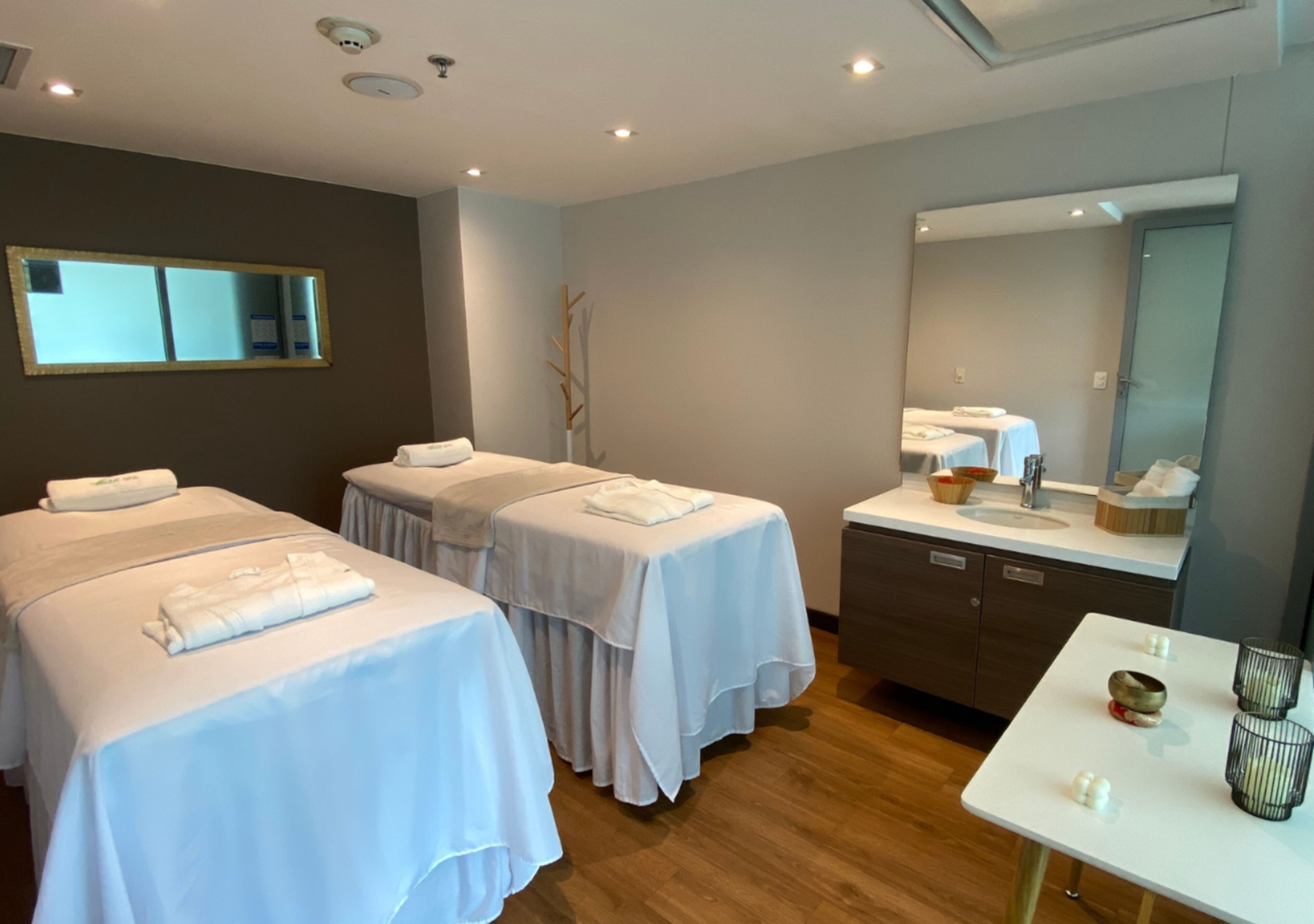 Habitación de hotel con dos camas, una mesita con velas, un espejo y un espacio para el baño.