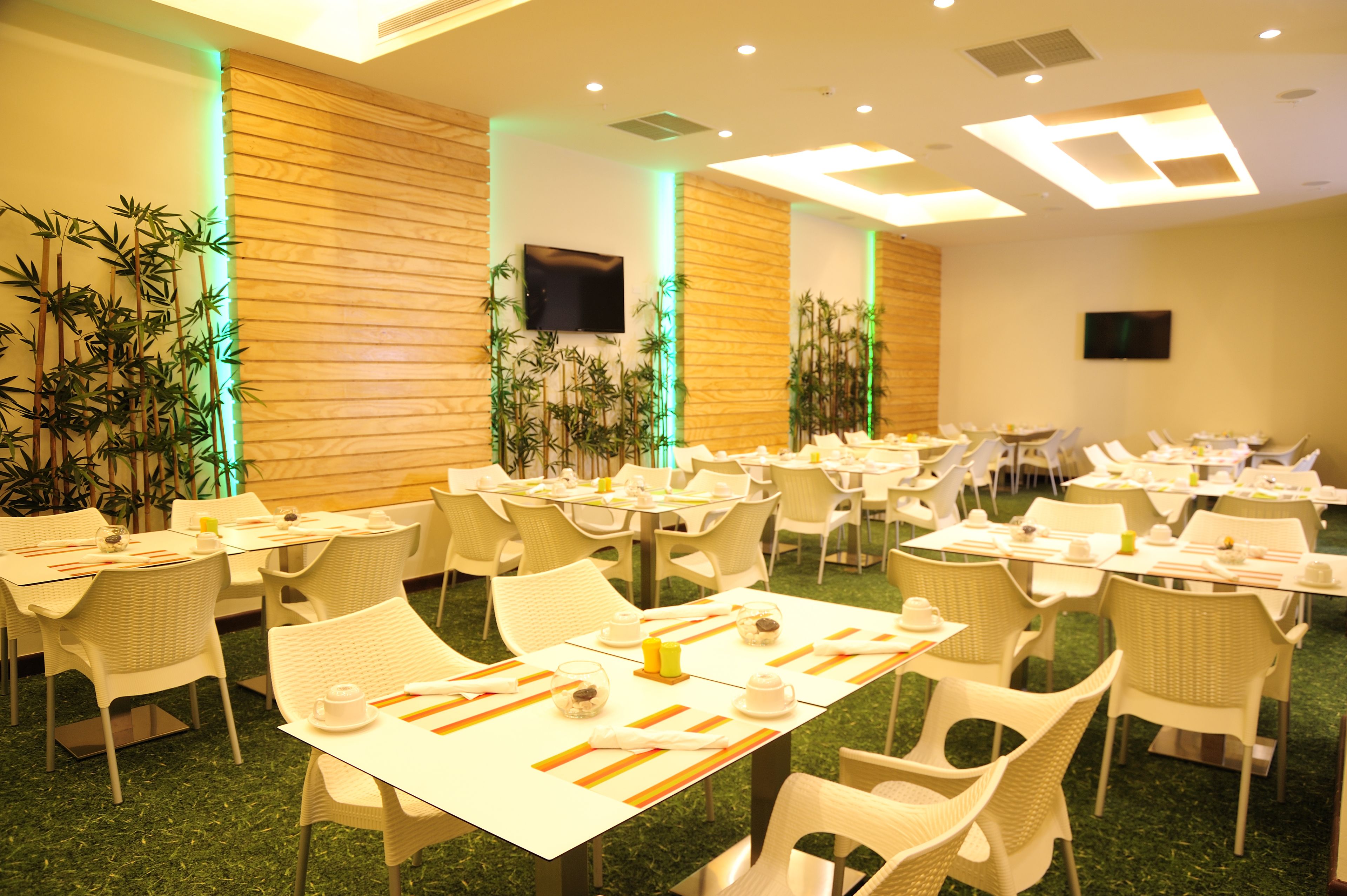 Comedor con mesas dispuestas para comidas, sillas y plantas decorativas.