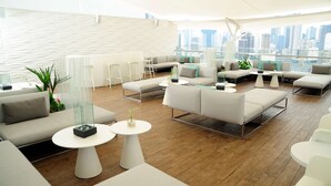 A modern lounge area with white furniture, glass tables, and a city view. - Best Western Plus Panama Zen Hotel (Panama City)