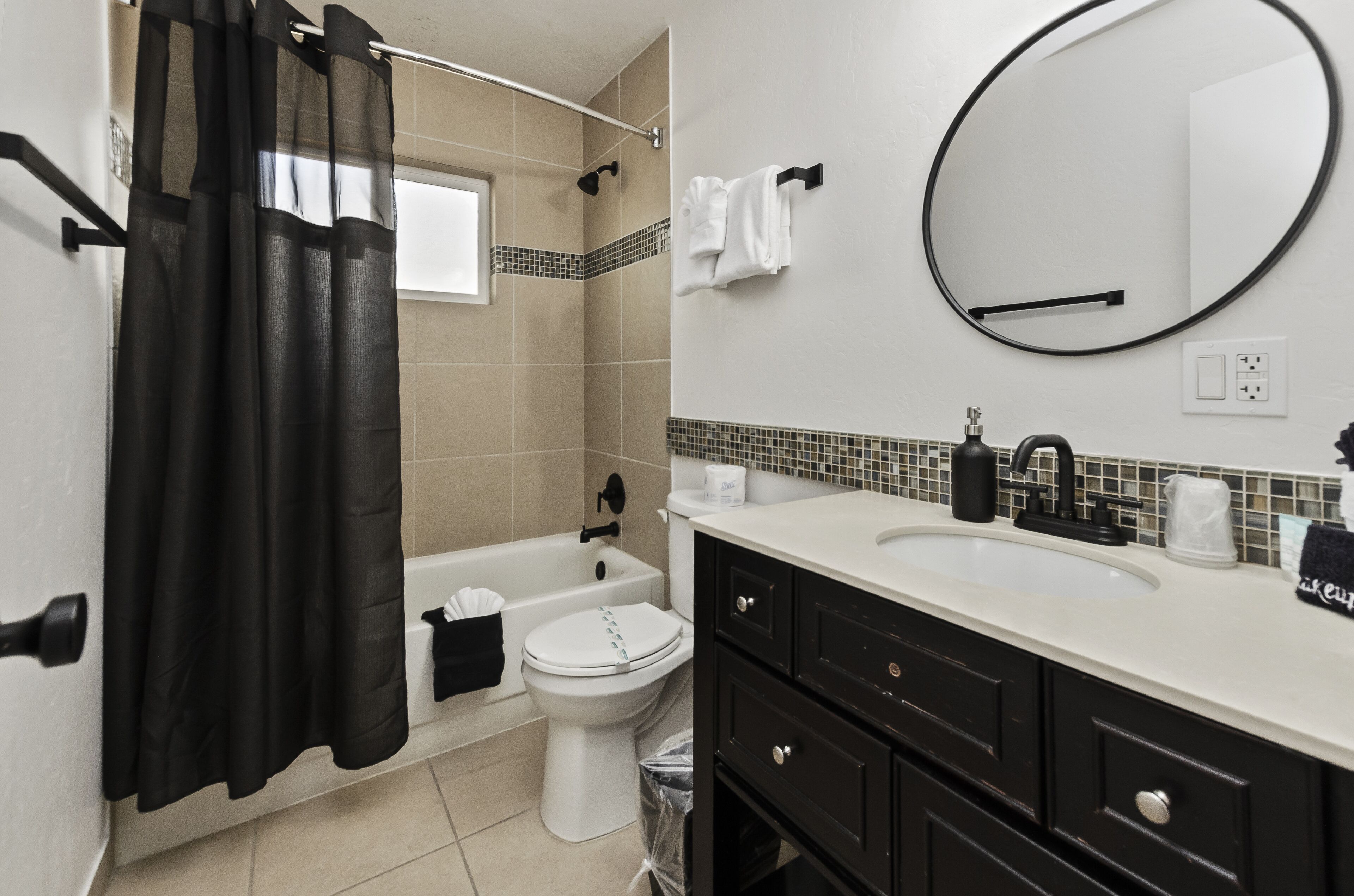 Un baño con bañera, inodoro, lavamanos y espejo.