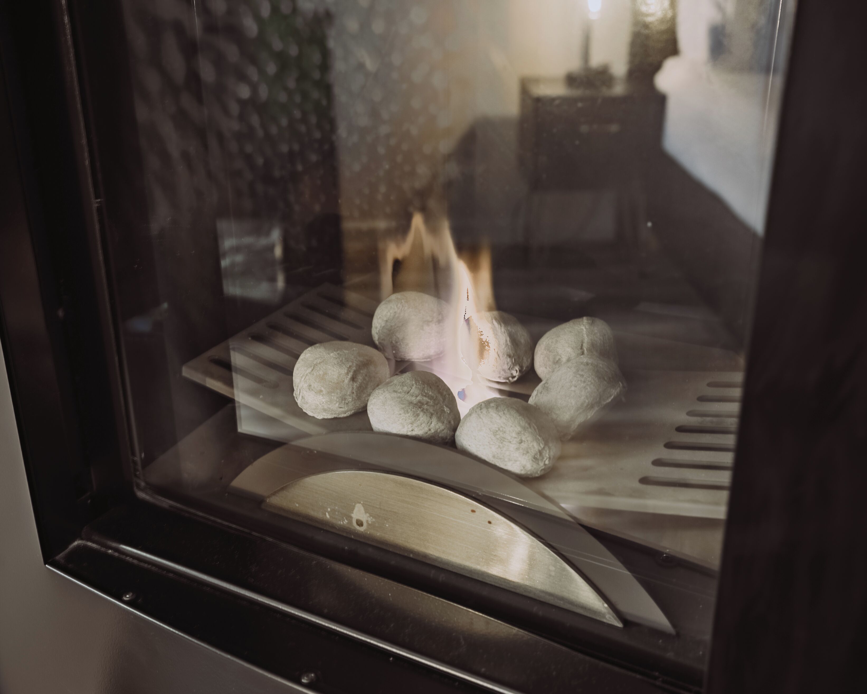 A stone wall and a window with a view of a room.