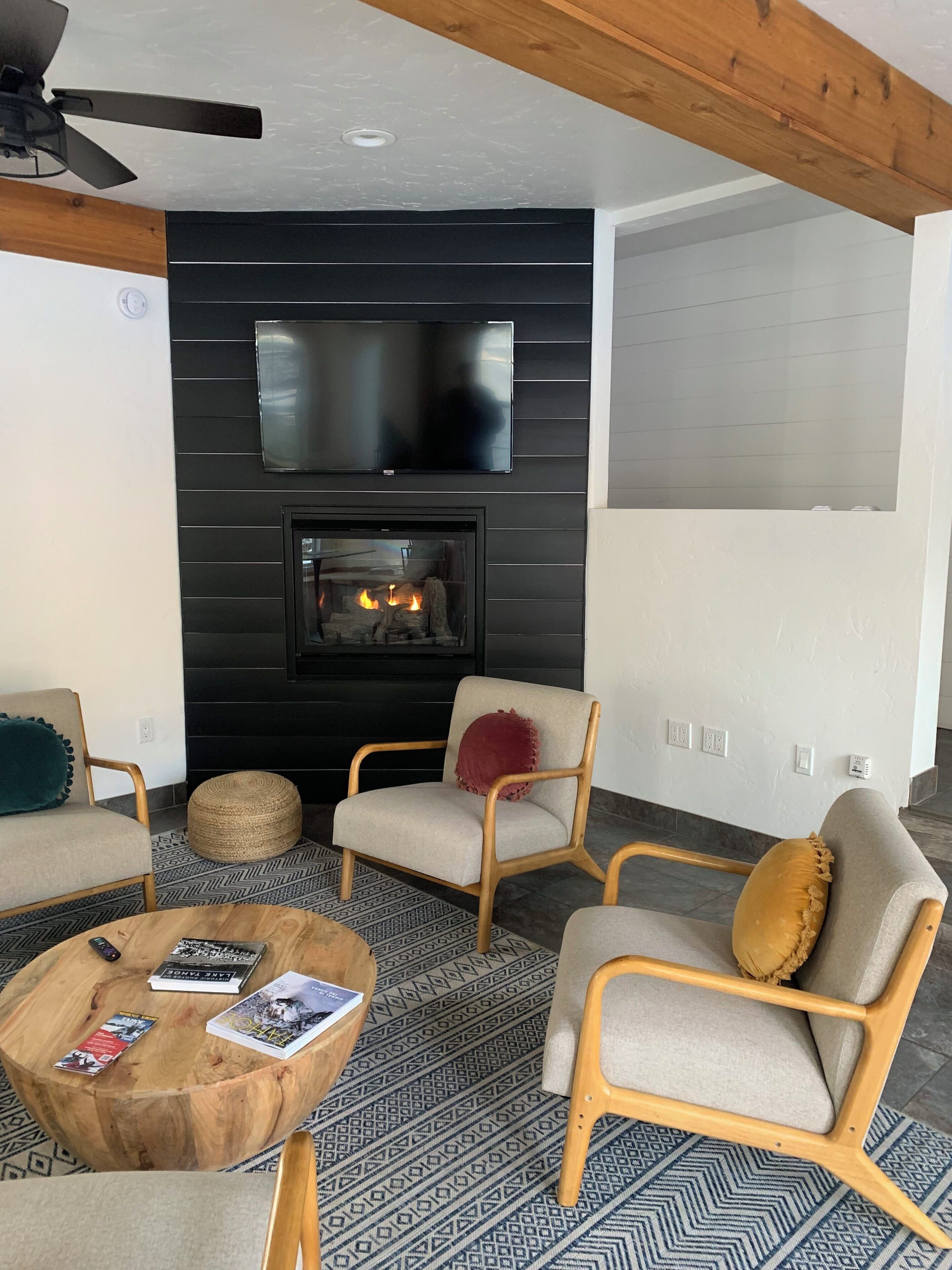 A modern living room with a fireplace, comfortable seating, and a flat-screen TV mounted above the fireplace.