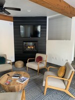 Una sala de estar moderna con chimenea, asientos cómodos y un televisor de pantalla plana sobre la chimenea.