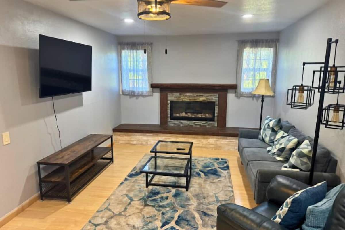 A living room with a flat-screen TV, a fireplace, a sofa, a coffee table, and a patterned rug.