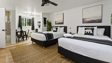 A modern hotel room with two beds, a ceiling fan, and artwork on the walls.