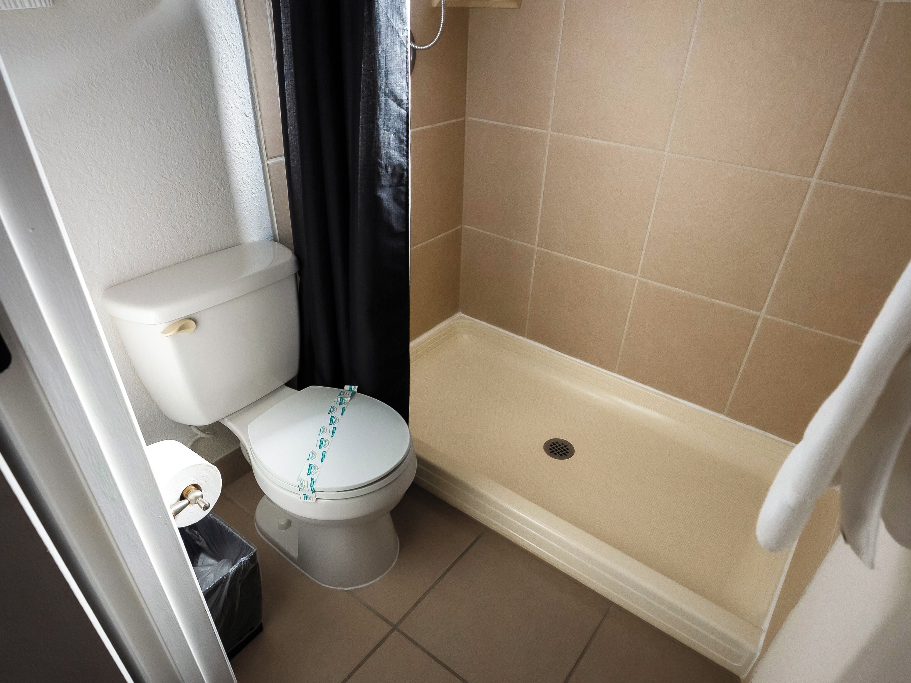 A small bathroom with a toilet, a shower area, and a bathtub.