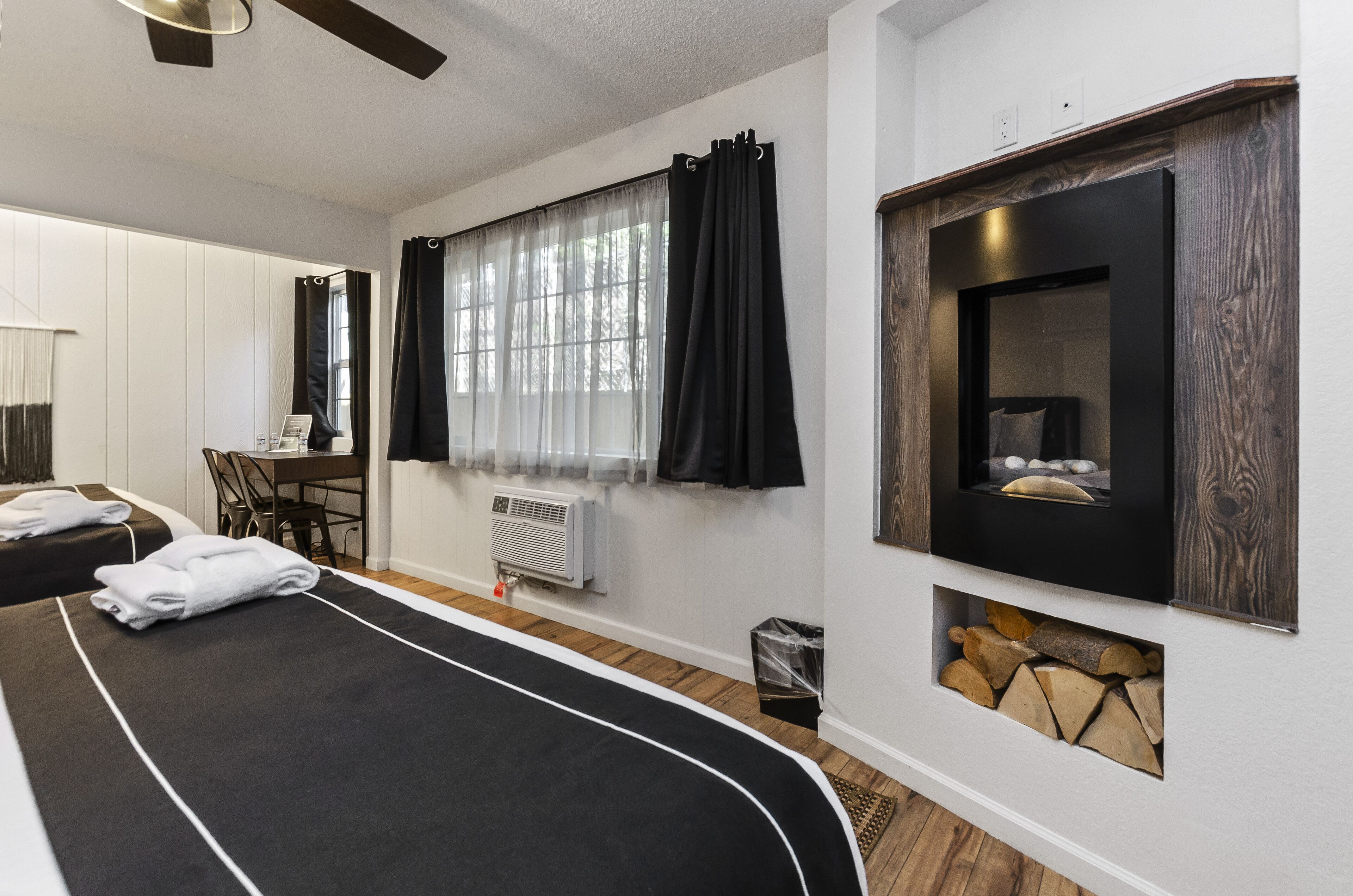 A hotel room with a large bed, a desk, and a fireplace.