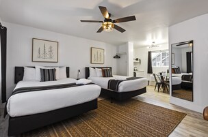 Une chambre moderne avec deux lits, un ventilateur de plafond et un grand miroir.