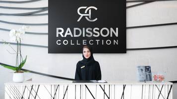 Una mesa de recepción con un letrero que dice "RADISSON COLLECTION" y una orquídea en maceta.