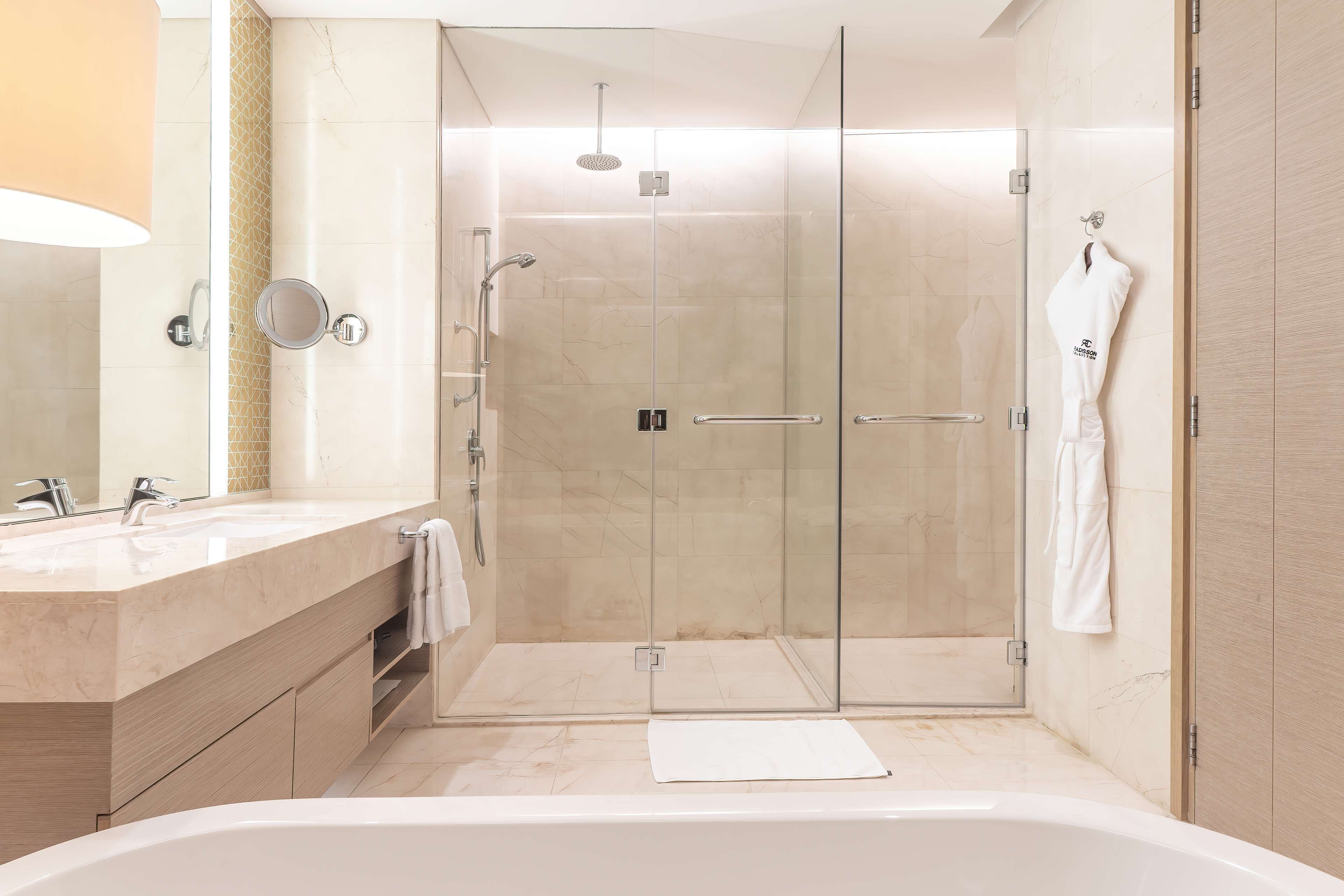 A modern bathroom with a glass-enclosed shower, a large bathtub, and a vanity with a mirror and two sinks.