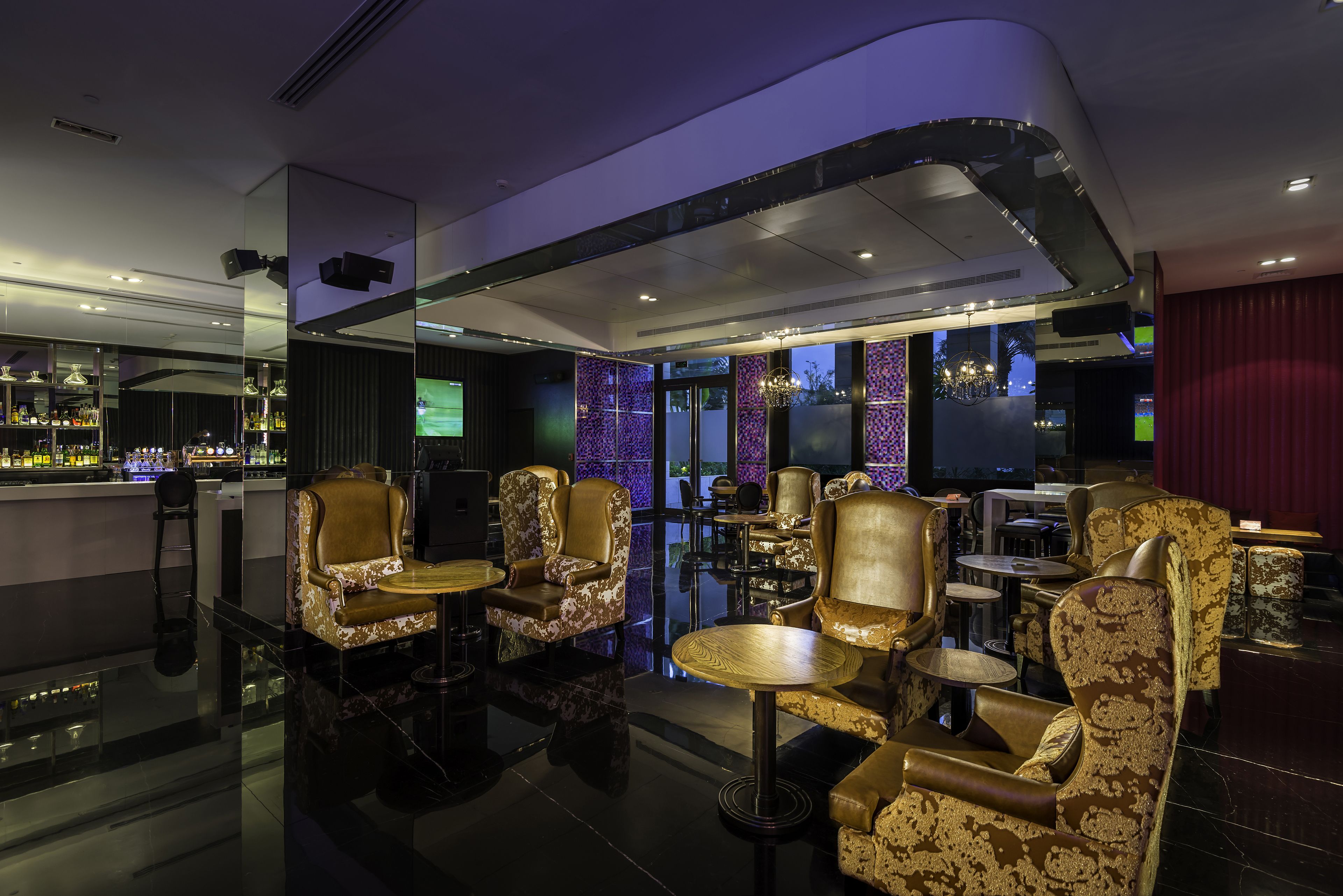 A modern bar area with high-end furniture, a polished floor, and ambient lighting.