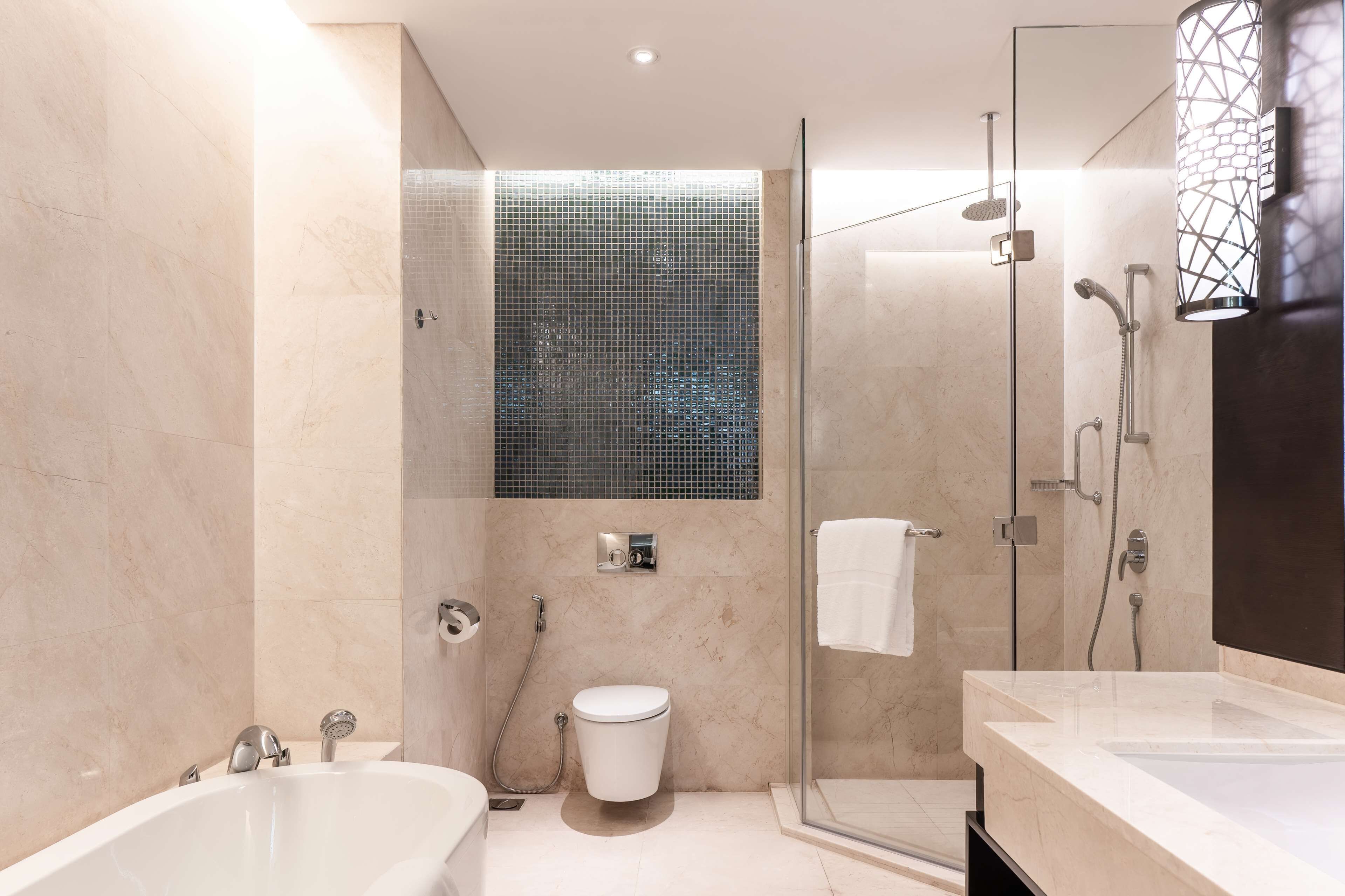 A modern bathroom with a glass-enclosed shower, a standalone toilet, and a bathtub.
