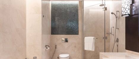 A modern bathroom with a glass-enclosed shower, a standalone toilet, and a bathtub.