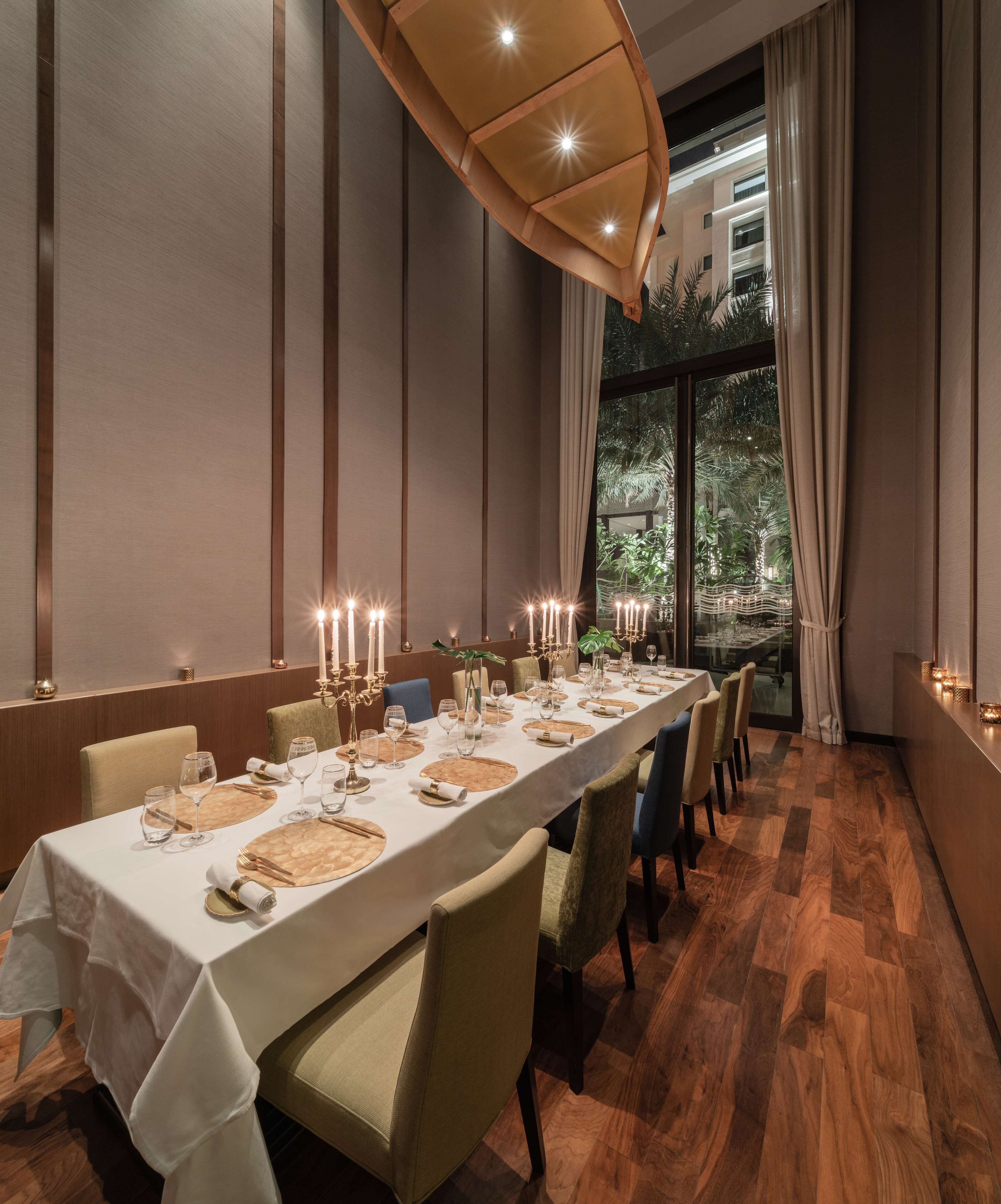 Una larga mesa de comedor dispuesta para una comida, con velas y cristalería.