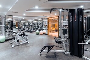 Ein modernes Fitnessstudio mit verschiedenen Trainingsgeräten, einer Spiegelwand und einer Bank.