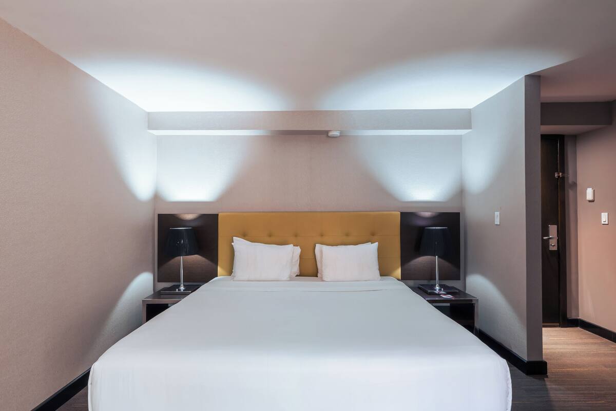 A hotel room with a large bed, two bedside tables, and a headboard.