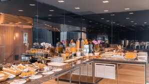 Moderni hotellin buffet, jossa on laaja valikoima erilaisia ruokia, kuten leivonnaisia, hedelmiä ja juomia.