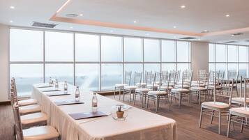 A conference room with a long table, chairs, and large windows offering a view.