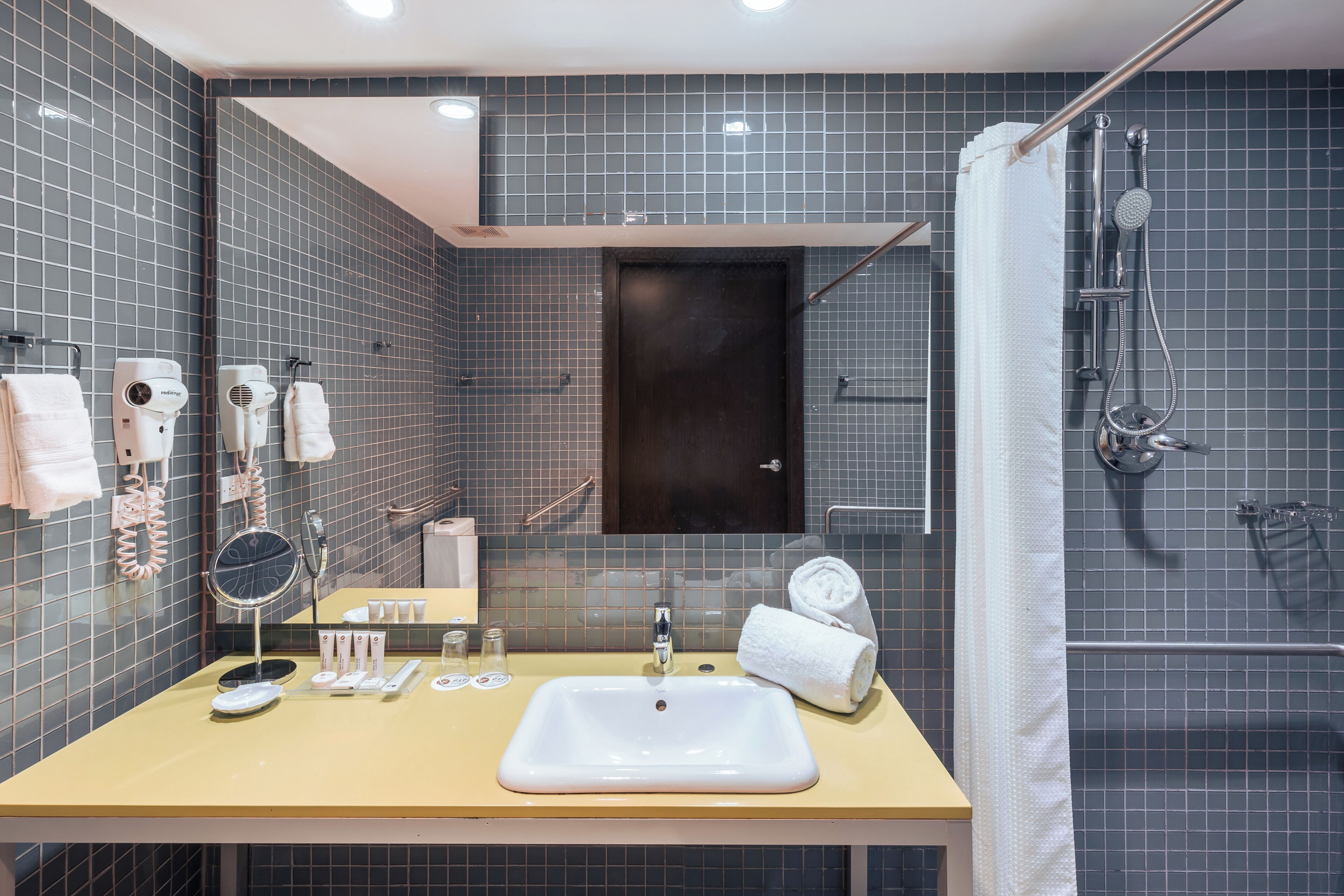 A bathroom with a sink, mirror, towel rack, and shower.