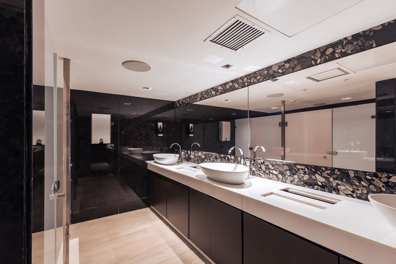 Un bagno moderno con due lavabi, pareti in marmo scuro e un grande specchio.