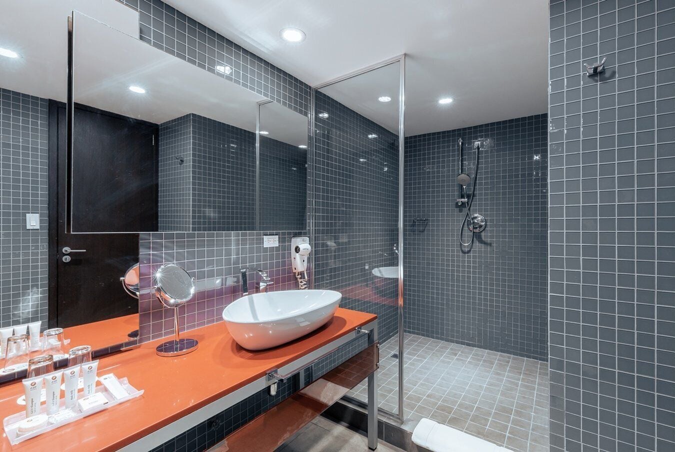 Une salle de bain moderne avec un grand miroir, un lavabo blanc et un espace douche.